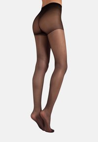 Pantys de encaje negros transparentes en las piernas y caderas, mostrados desde atrás, con los pies ligeramente levantados en puntas contra un fondo blanco liso.