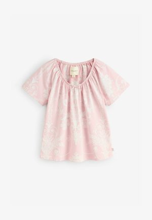 Roza bombažna majica s širokim izrezom, kratkimi rokavi in zapletenimi belimi cvetličnimi vzorci po vsej površini. Nabran akcent na izrezu.