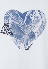 Balta marškiniai su mėlynu širdies piešiniu ir džinsiniu dizainu, o tekstas sako "MES MYLIME DŽINSUS." Apačioje dešinėje pusėje parašyta "Pepe Jeans."