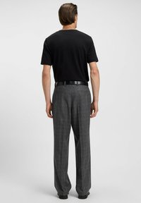 Svart kortärmad t-shirt i kombination med höga grårutiga byxor. Byxorna har rak passform och sidofickor. Svart bälte ingår.