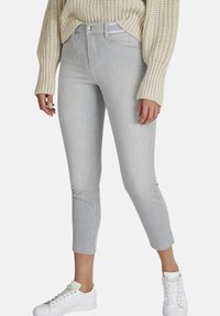 Grijs en wit gestreepte cropped jeans met een fitted ontwerp, voorzakken en een metalen knoopsluiting, gecombineerd met witte sneakers.