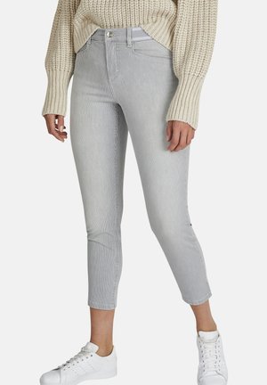 Grau und weiß gestreifte, taillierte Jeans mit einem engen Schnitt, seitlichen Taschen und einem metallischen Knopfverschluss, kombiniert mit weißen Sneakers.