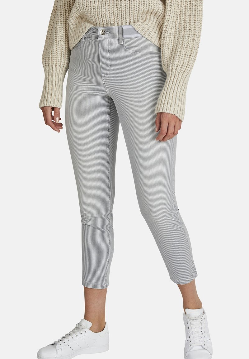 Grijs en wit gestreepte cropped jeans met een fitted ontwerp, voorzakken en een metalen knoopsluiting, gecombineerd met witte sneakers.