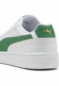 Sneaker bianche con dettagli verdi, superiori in pelle e materiale sintetico, lati texturizzati, dettaglio del logo dorato, colletto imbottito e suola in gomma.