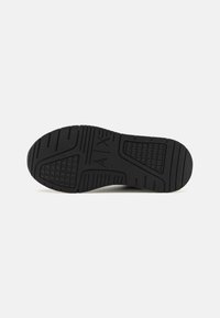 Semelle de sneaker en caoutchouc noir avec des motifs de traction texturés et un logo, dotée d'une construction durable et flexible conçue pour le confort.