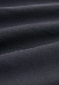 Schwarzer Baumwollstoff mit glatter Textur, diagonal gerippten Mustern und subtiler Schimmerung, in sanften Falten drapiert.