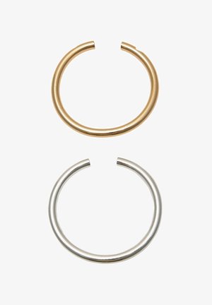 Dve odprti kovinski krožni obroči, en zlat in en srebrn, prikazani vertikalno na belem ozadju.