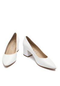 Białe skórzane buty na słupku z pointed toe. Gładka tekstura, minimalistyczny design i widoczna wewnątrz wyściółka.