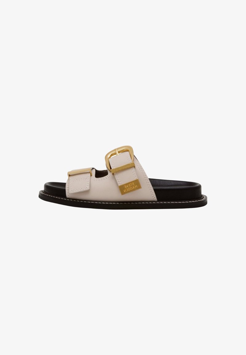 Cream leather slide sandal featuring two gold buckles, black sole, and white stitching detail along the edge. Brand logo displayed prominently.