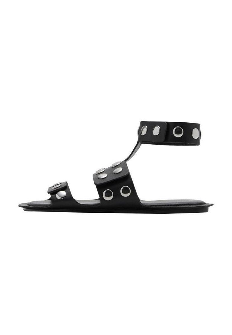 Svarta platta sandaler med flera remmar och cirkulära silvernitar. Har en stilren design och slät yta. Öppen häl och tåområde.