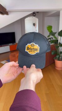 Melna cepure ar tīkliņa aizmuguri, priekšpusē redzama izteiksmīga dzeltenas un melnas "Brixton" logotipa plāksteris. Regulējama siksniņa izmēra pielāgošanai.