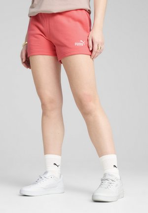 Pink athletic shorts with an elastic waistband and embroidered Puma logo, paired with white sneakers and ribbed crew socks.