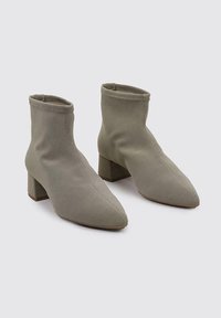 Bottes chelsea couleur kaki en tissu texturé, avec un bout pointu et un talon épais, dotées de coutures invisibles et d'une ouverture élastique.