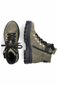 Bottes de cheville en suède vert olive avec semelles en caoutchouc noir, lacets noirs et œillets en métal doré. Elles présentent une fermeture éclair sur le côté et des détails texturés.