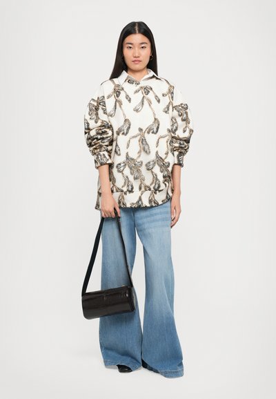 Off-white pullover with textured floral pattern; wide blue jeans; black glossy cylindrical handbag; relaxed fit with puff sleeves.