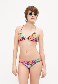 Bikini komplet z rjavim podlagom in večbarvnimi cvetličnimi vzorci v oranžni, roza in modri barvi; vključuje trikotno zgornji del in spodnji del v slogu kratkih hlač.