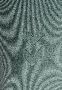 Gestreepte groene textiel met een gegraveerd pijlpatroon in het midden, wat zorgt voor een textuur en een passende uitstraling.