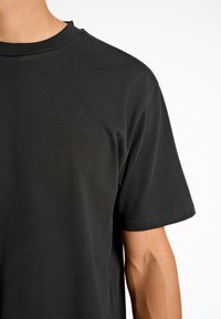 T-shirt in cotone nero con collo rotondo, maniche corte e una texture liscia. Design semplice senza motivi o accenti visibili.