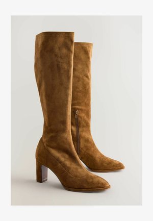 Bruine suède kniehoge laarzen met een spitse neus, blokhak en een ritskraag aan de zijkant. De textuur is glad en zacht.
