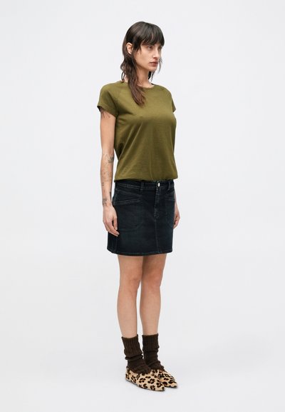 Λαδί πράσινο t-shirt με κοντά μανίκια, συνδυασμένο με σκούρα μίνι φούστα από τζιν. Φορεμένο με καφέ ριγωτές κάλτσες και παπούτσια με λεοπάρ τύπωμα.