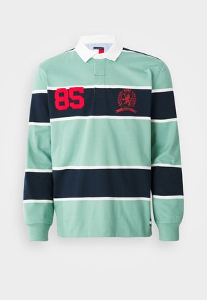Rugby majica s dolgimi rokavi z zelenimi in temno modrimi vodoravnimi črtami, belim ovratnikom, rdečim številom "85" in grbom na prsih.