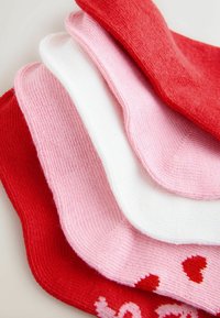 Zestaw czterech skarpetek za kostkę w kolorach czerwonym, różowym i białym. Cechuje je prążkowana faktura oraz wzór serc na czerwonej skarpetce. Wykonane z miękkiego materiału, w stylu casual.