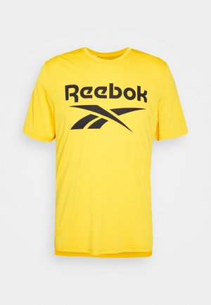Żółta koszulka z krótkim rękawem z czarnym logo Reebok i tekstem wyśrodkowanym z przodu na białym tle.