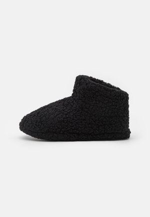 Black, cozy slippers made of textured fabric, featuring a high, rounded collar and a flexible sole for comfort.