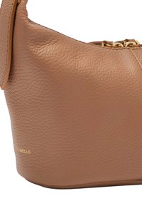 Borsa a tracolla in pelle tan con una finitura texturizzata. Presenta una forma arrotondata, una cerniera superiore e dettagli in oro. Logo del marchio impresso di lato.