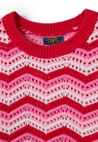 Maglione lavorato a maglia con scollatura rotonda caratterizzato da un motivo a zigzag in rosso, rosa e bianco. Include un'etichetta con "OVS kids" all'interno del colletto.
