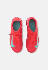 Red athletic shoes with a textured design, featuring turquoise accents and laces. The interior has a contrasting light blue insole.
