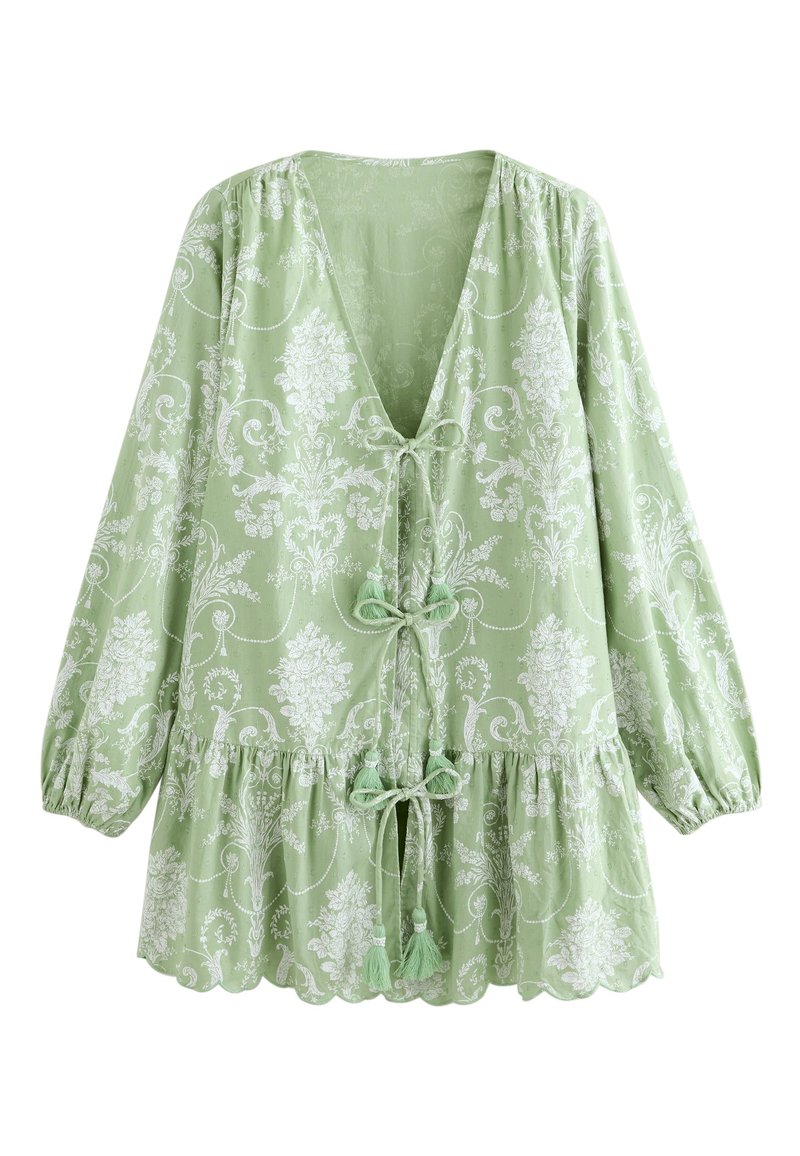 Grün gemusterte Bluse mit tiefem V-Ausschnitt, gerafften Ärmeln und dekorativem Bindeschluss. Mit floralen Motiven und einem gerüschten Saum.