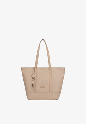 Sac fourre-tout en cuir beige avec deux longues poignées, une poche avant, et un pompon décoratif ainsi qu'un pendentif rond suspendus à l'une des poignées.