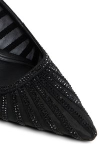 Černý černošpičatý podpatek s texturovanou tkaninou a perlovými ozdobami. Má pruhované vnitřní podšívku a elegantní siluetu.