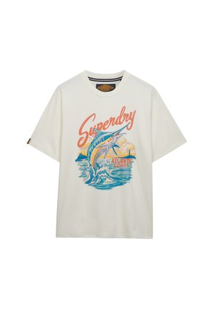 T-shirt blanc avec le texte "Superdry", un marlin sautant au-dessus des vagues de l'océan, et "Atlantic Coast" en couleurs de coucher de soleil.