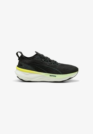 Schwarzer niedrig geschnittener Laufschuh mit gestricktem Obermaterial, dicker weißer Sohle mit gelbem Akzent, schwarzen Schnürsenkeln und "NITRO"-Markierung an der Seite.