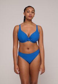 Blauwe bikini set met een gevormde cuptop met een strikdetail aan de voorkant en bijpassende laag uitgesneden onderkant, zachte textuur en een minimalistisch ontwerp.