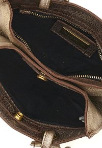 Interno di una borsa in pelle marrone con texture, foderato in tessuto blu navy, due scomparti con cerniere dorate e una piccola etichetta del marchio.