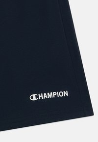 Navyblauwe katoenen t-shirt met ronde hals. Bevat een witte "CHAMPION" logo nabij de zoom. Soepele textuur, korte mouwen en een losse pasvorm.