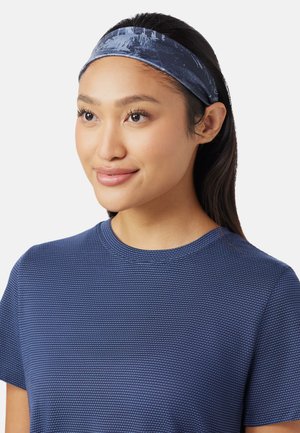 Marineblaue Stirnband aus weichem Stoff mit glatter Textur; zeigt ein dezentes Muster. Kombiniert mit einem strukturierten blauen Hemd.