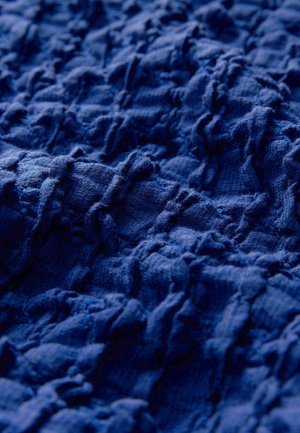 Gestructureerde marineblauwe stof met een gekreukt ontwerp en ongelijke ribbels, die een variërende oppervlaktediepte en een zachte, geweven uitstraling vertoont.