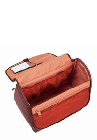 Borsa di stoffa marrone con interno arancione, dotata di chiusura a zip, tasche in rete per l'organizzazione e uno specchio attaccato da un gancio.