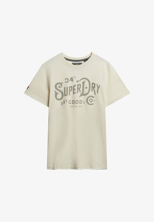 Jasnobeżowa koszulka z bawełny z logo "SuperDry" w ciemnoszarym kolorze. Krótkie rękawy i okrągły dekolt z prostym dołem.