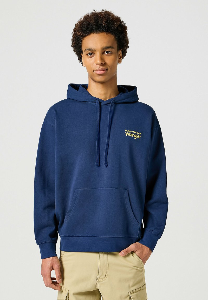Granatowy hoodie z kieszenią kangurką, kapturem ze sznurkiem i haftowanym żółtym logo "Wrangler" na lewej piersi. Miękka faktura materiału.