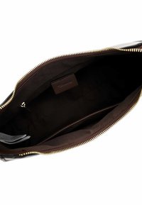 Brown interior of a zippered bag shows a smooth texture. Features a gold zipper and a small leather tag. The interior is dark and spacious.
