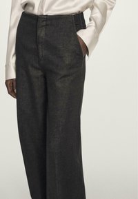 Sorte, højtaljede bukser lavet af struktureret stof, med sidelommer og lige ben.