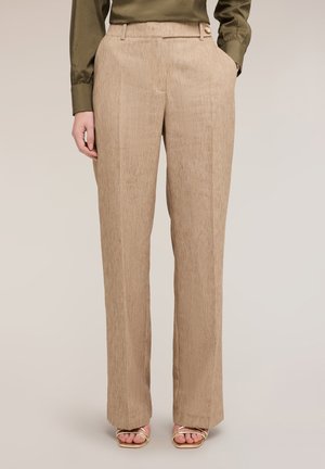 Beige teksturerede bukser med lige ben og sidelommer, kombineret med gyldne åbne hæle-sandaler og en olivengrøn top.