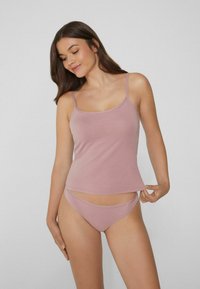 Jasnoróżowa koszulka na ramiączkach z cienkimi paskami oraz pasujące majtki o niskim stanie, wykonane z miękkiego, elastycznego materiału, o prostym kroju i gładkiej fakturze.