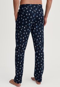 Marineblauwe pyjamabroek met ski-thema patronen in lichtblauw en wit. Elastische tailleband, rechte snit en zijzakken. Zachte stoftextuur.