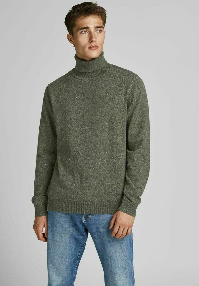 Maglione verde a collo alto in tessuto a maglia texture, con maniche lunghe e una vestibilità comoda, abbinato a jeans azzurri chiari.